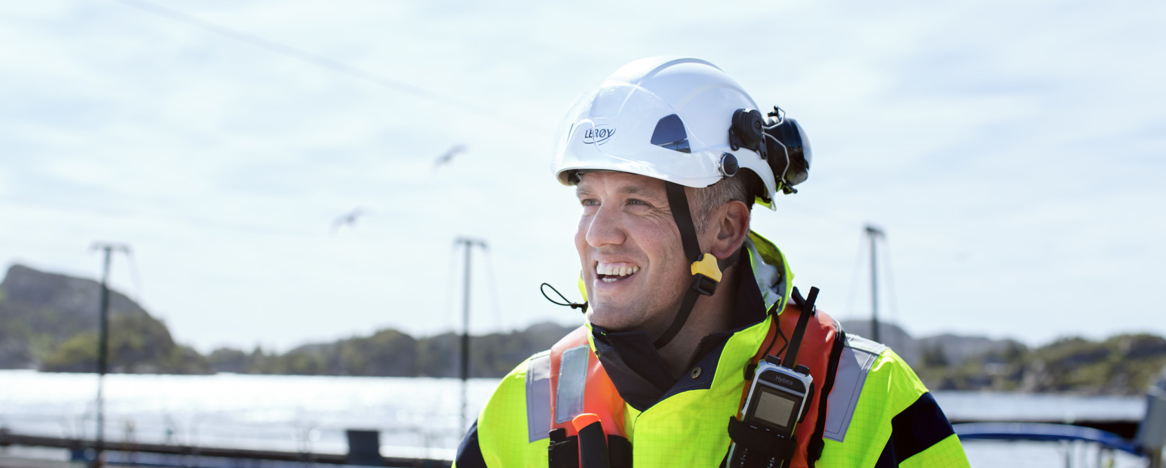 Lerøy employee in workwear and safety equiptment outside by an aquaculture faciltity