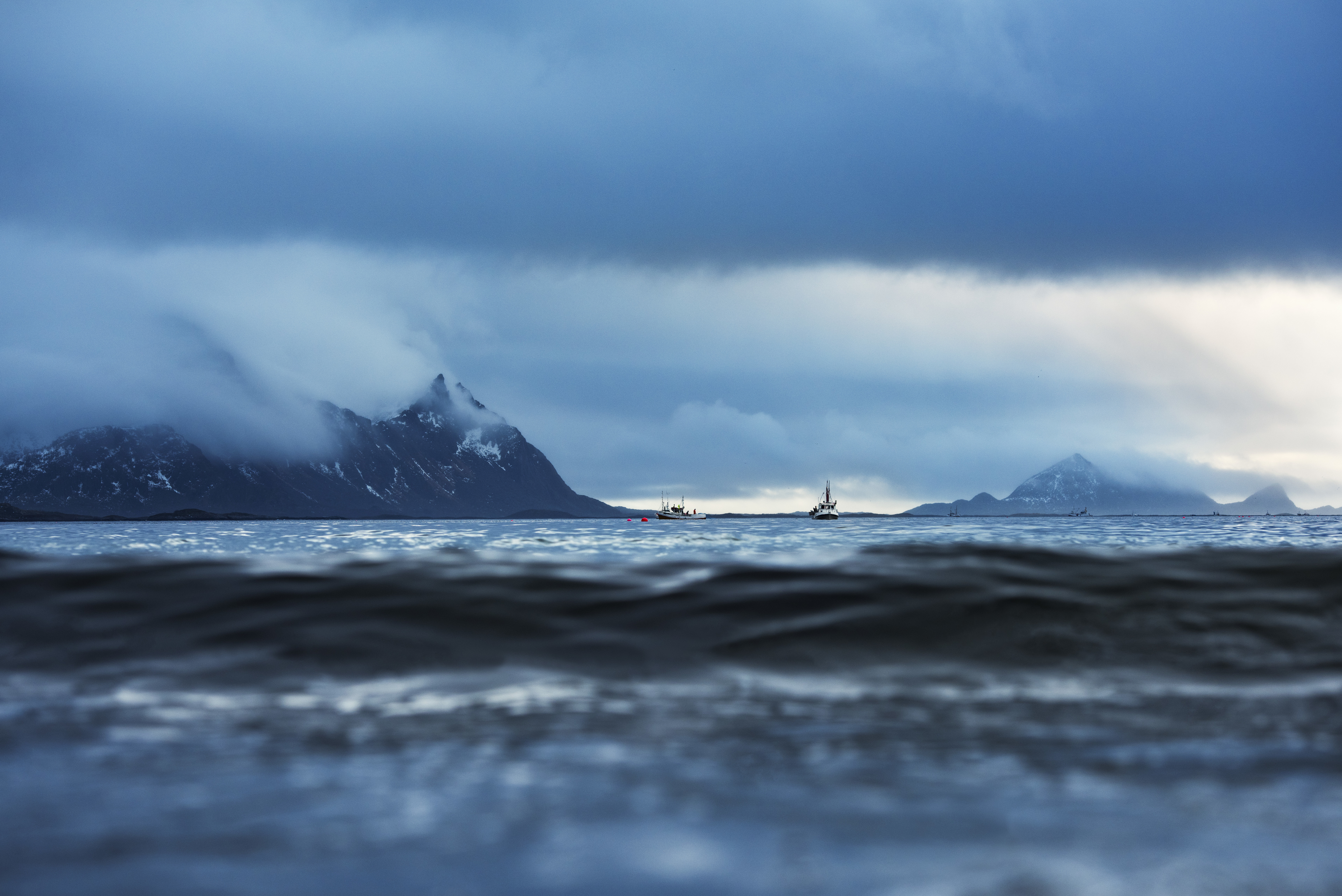 Fishing boats at sea with mountains in the background