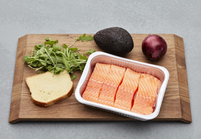 Lakseporsjoner og grønnsaker på skjærebrett